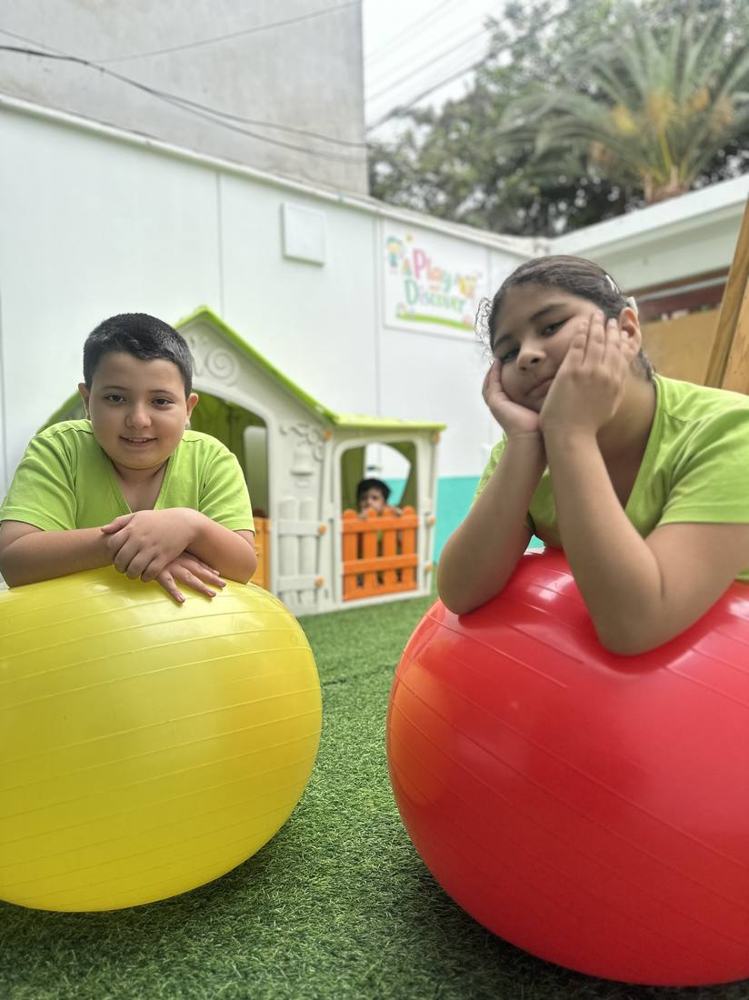 Niños jugando con pelotas grandes en el patio