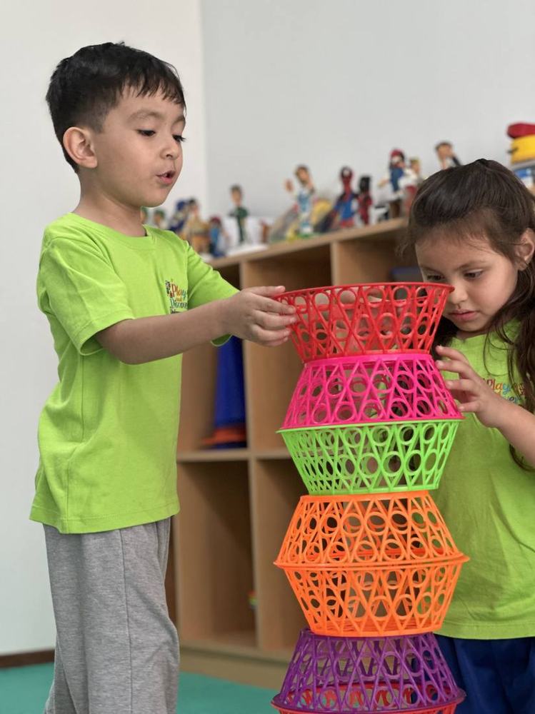 Niños armando una torre de canastas coloridas